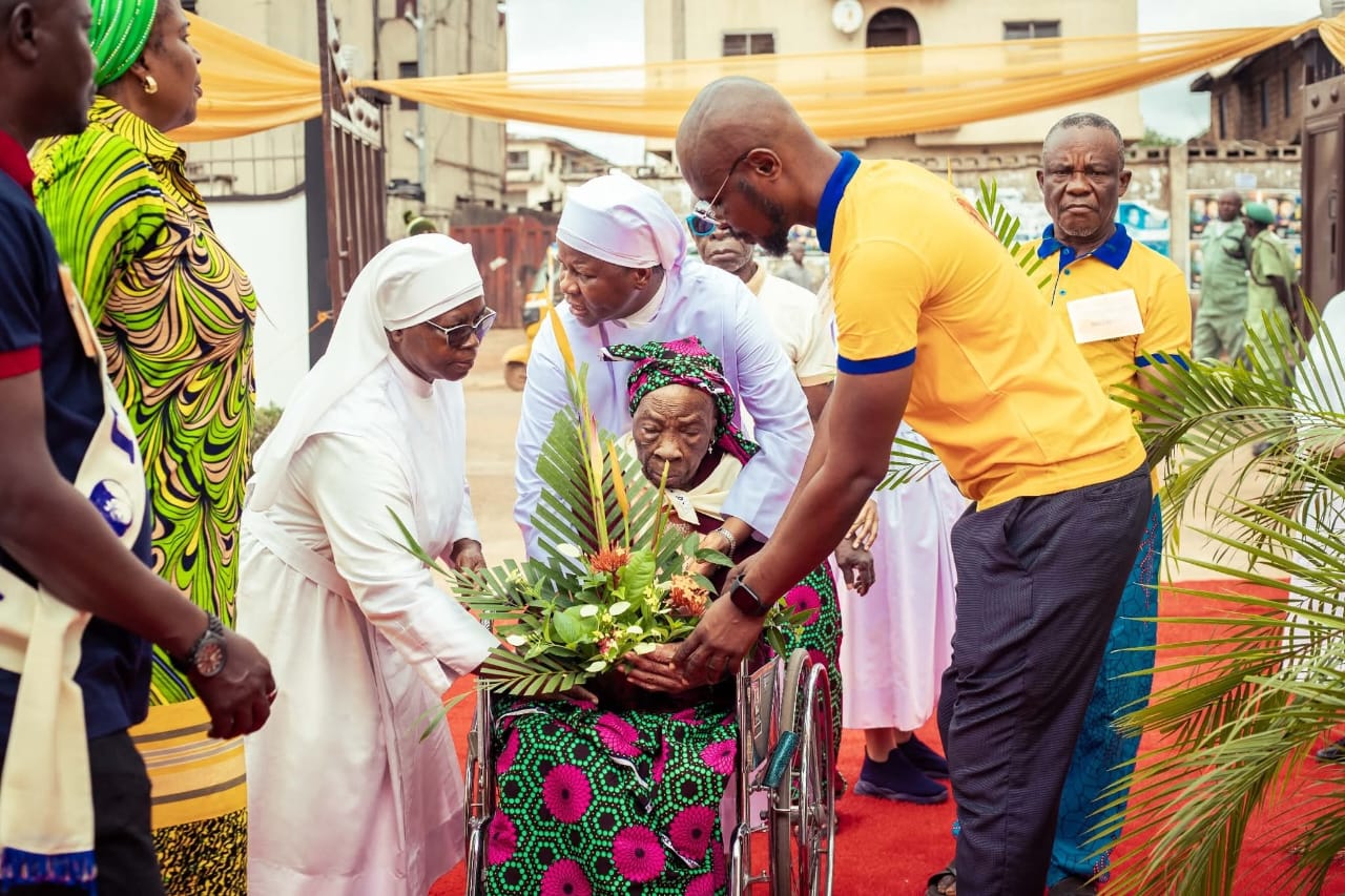 Sisters and guests welcoming a resident with flowers at Little Sisters Nursing Home.